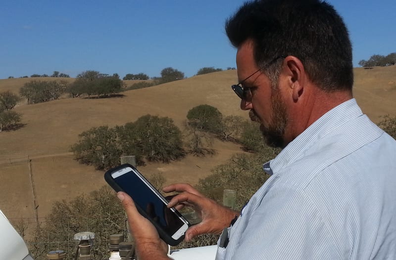 A propane operator checks a rugged phone at a tank site — the same hands-on verification this page's audit tool runs digitally.
